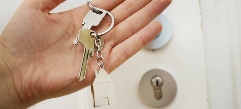 A person holding house keys in front of a door