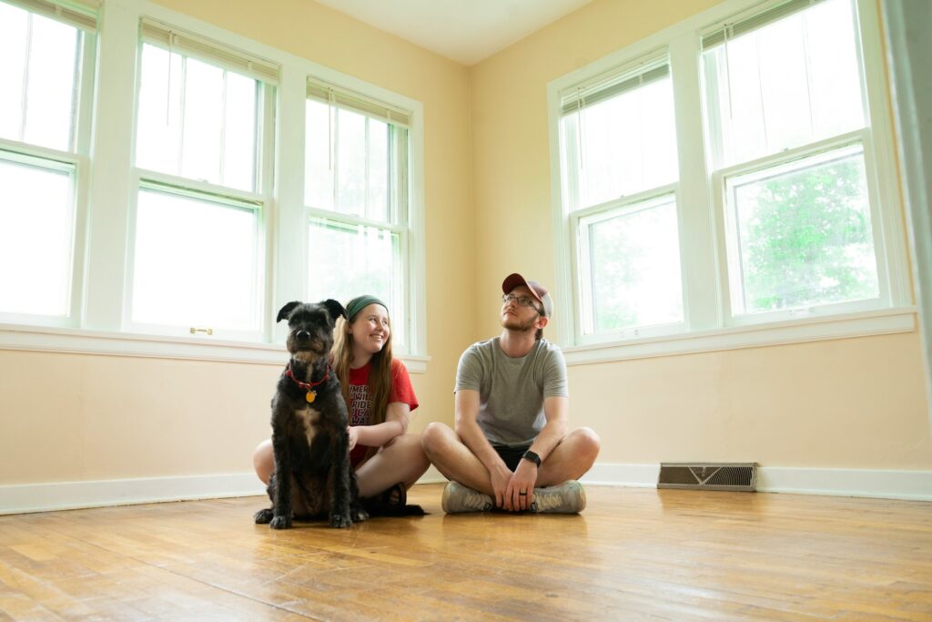 A couple sitting in their new home's empty living room