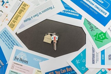 A house key surrounded by leaflets.