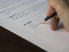 A person writing their signature on paper.